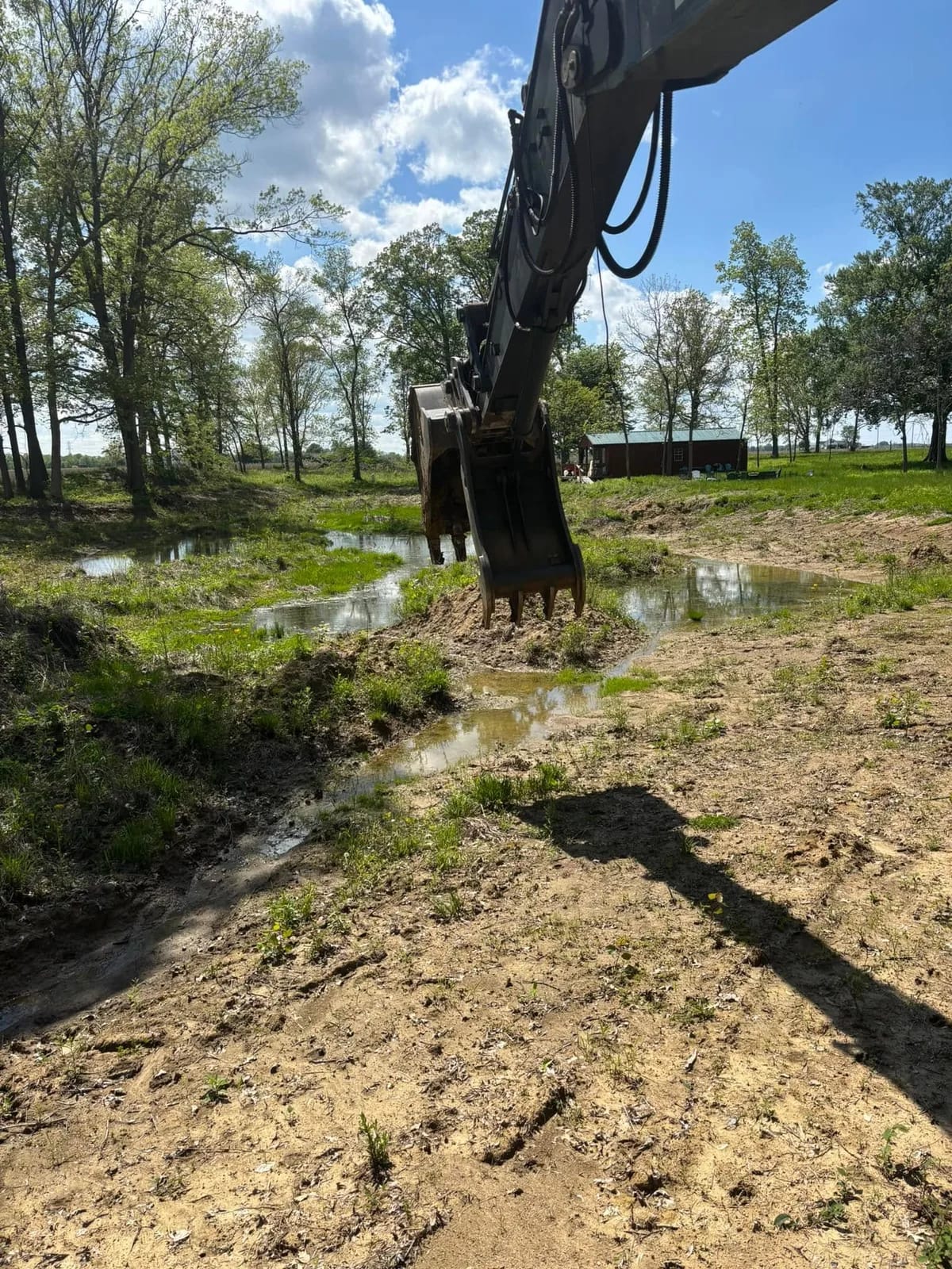 Excavator arm working wet ground at a pond edge