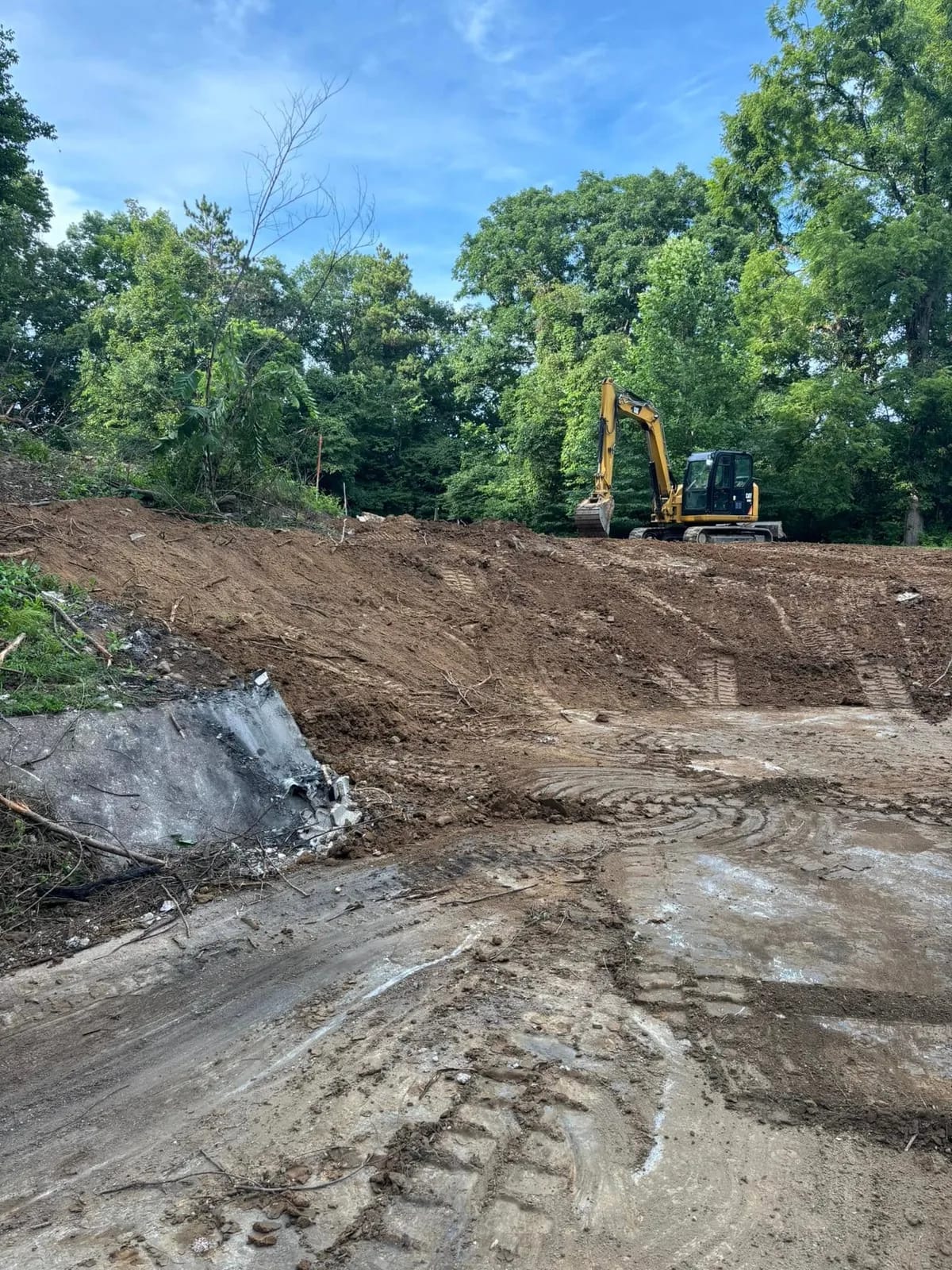 K&H excavator working a dirt site with spoil piled to one side
