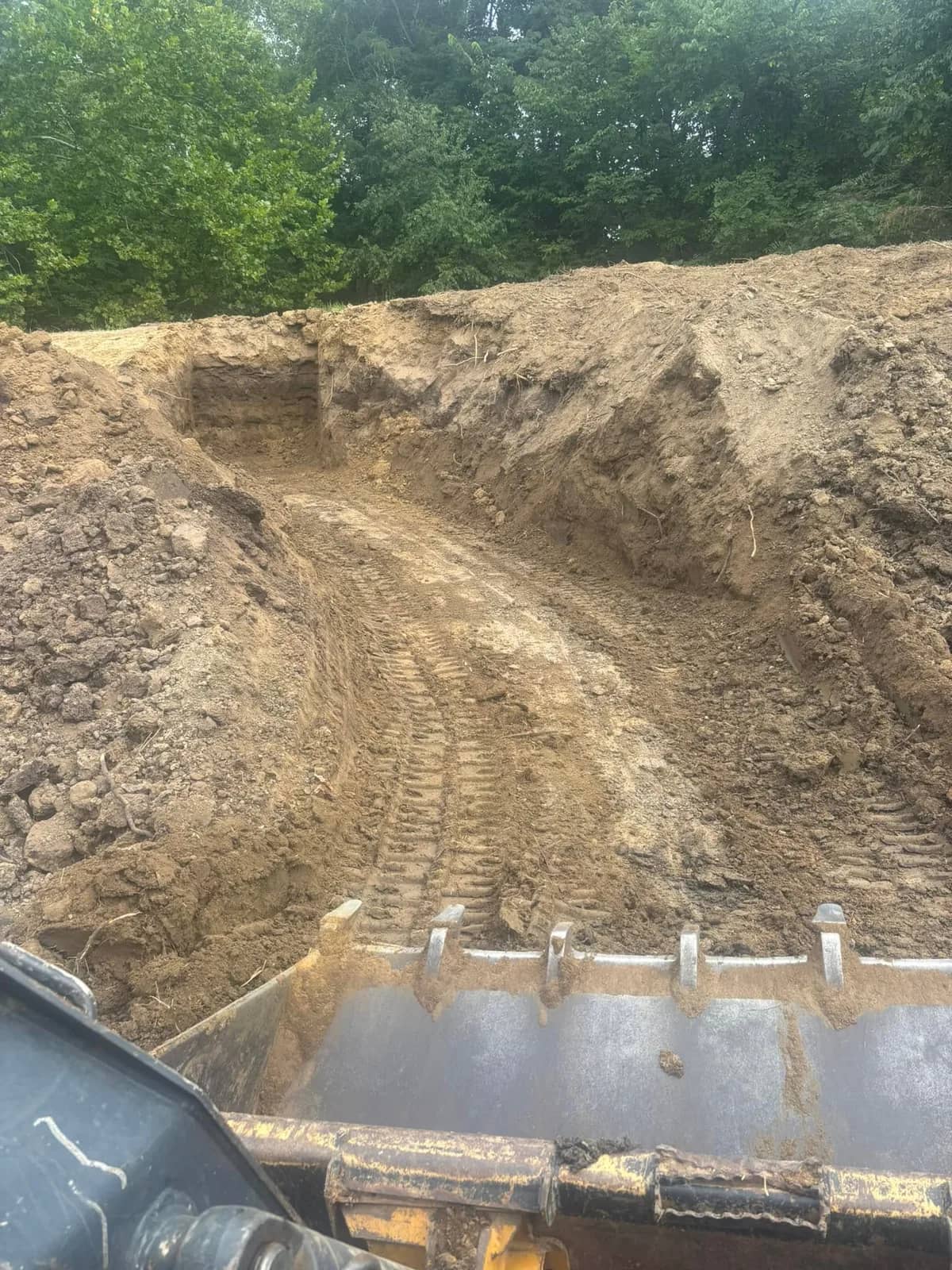 Excavator bucket digging into a dirt bank