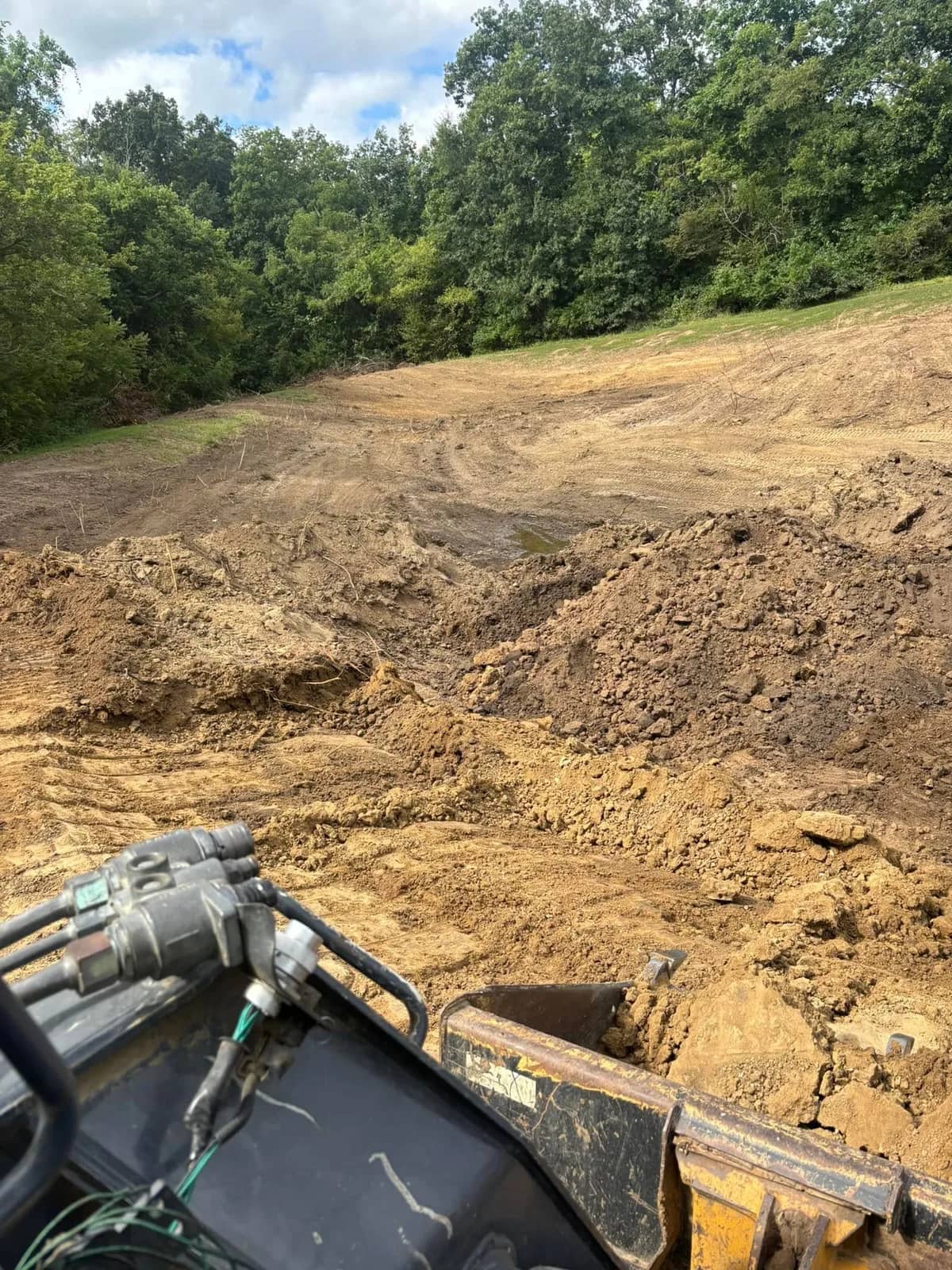 Excavator moving a pile of dirt on an open site