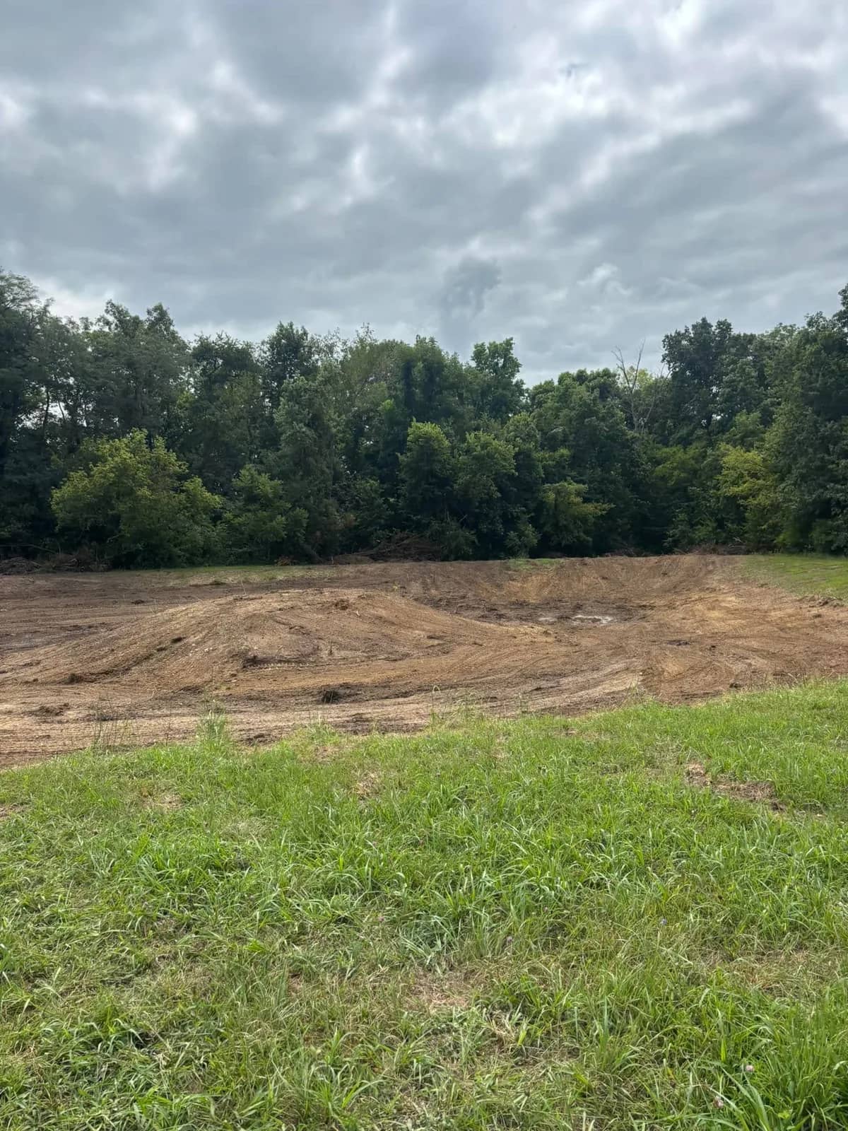 Graded pond site under an overcast sky